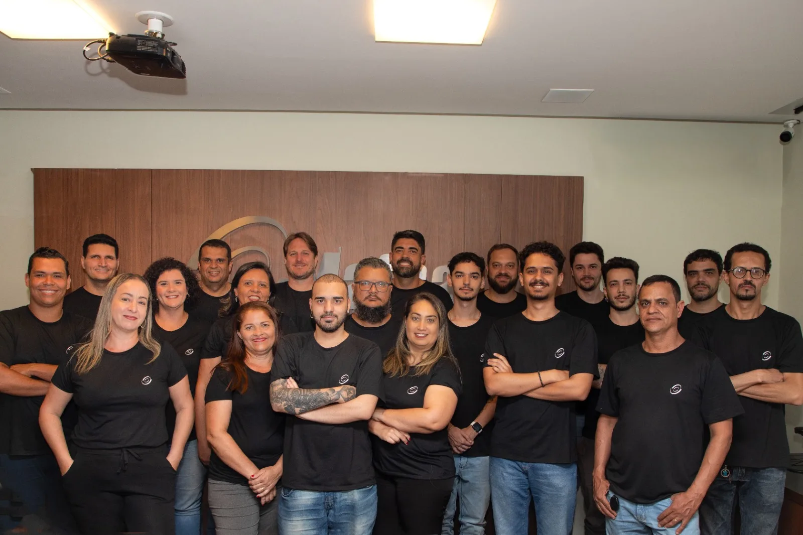 Equipe da Mafra Informática reunida no auditório, em frente à marca da empresa