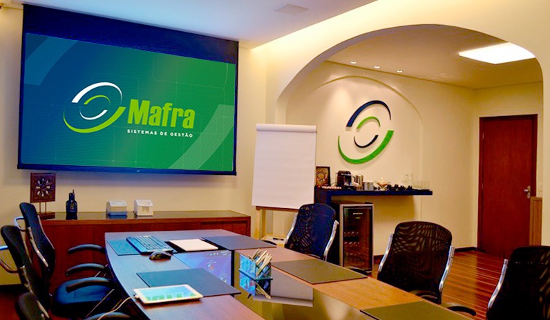 Sala de reuniões da Mafra Informática com a marca na parede e no telão