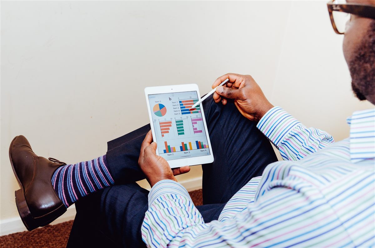 Empresário analisando gráficos de barras e de pizza com os resultados do negócio na tela de um tablet